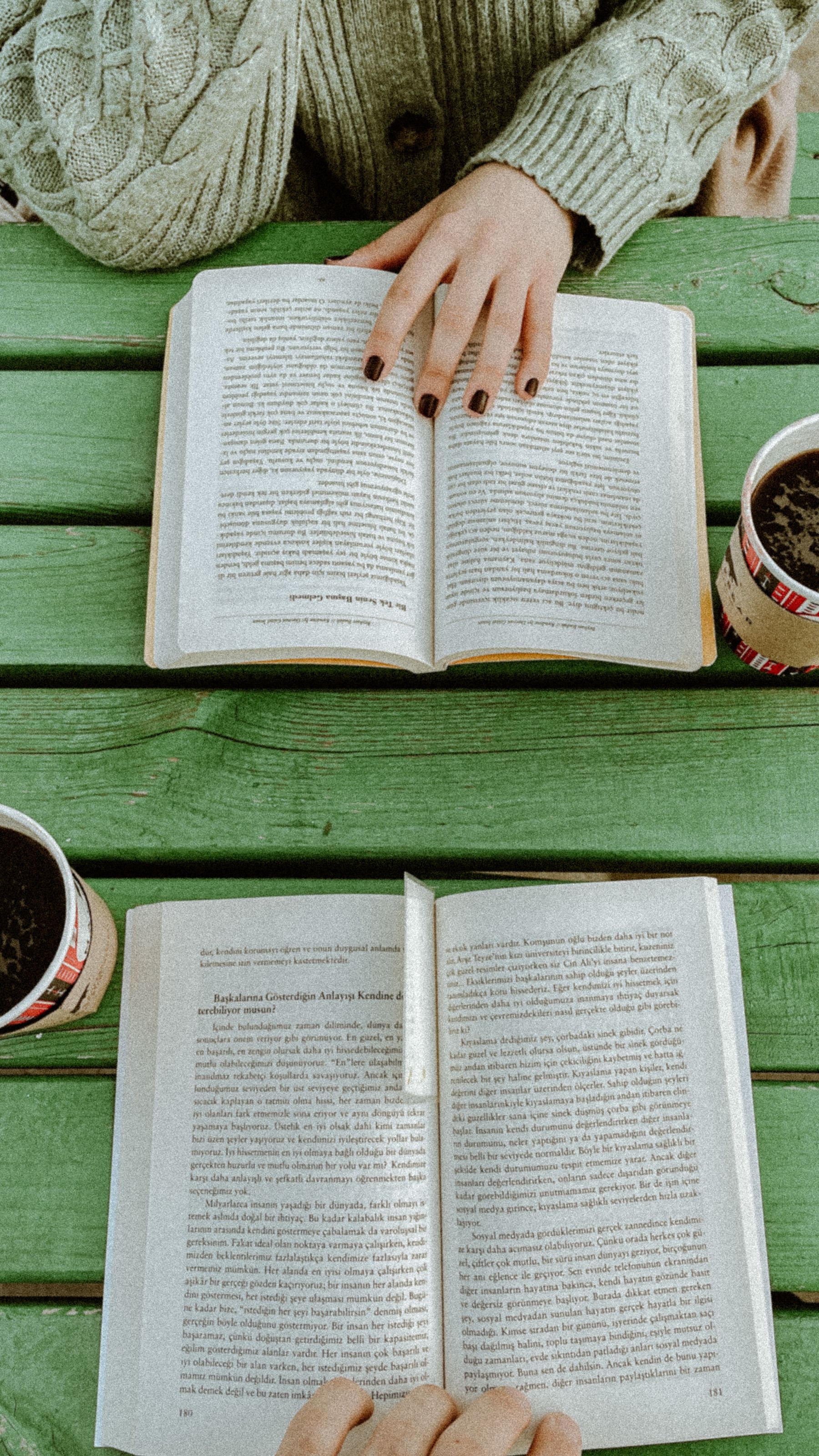 Open books and coffee on a green table